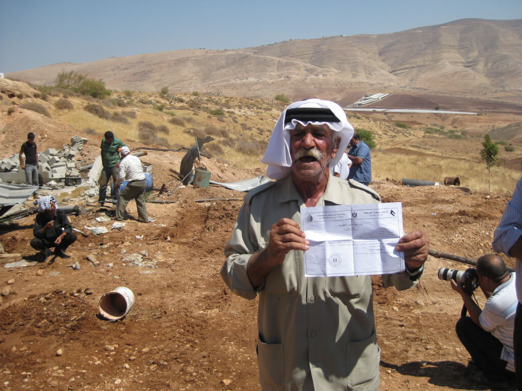 Farmer holds up permit for his water well that has just been demolished. 