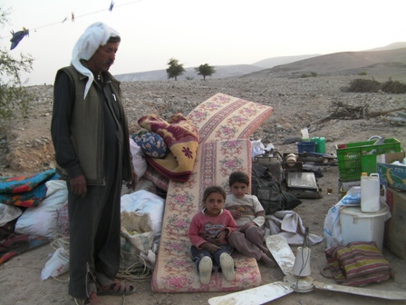 Abu Nahar and two of his daughters with the remains of their home