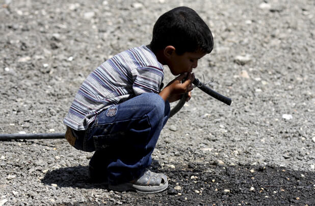   A Palestinian Bedouin child drinks water on a road between Jericho and Ramallah; Bedouins in the West Bank have access to as little as 10 liters of water per day.  (Eyad Jadallah / APA images) 