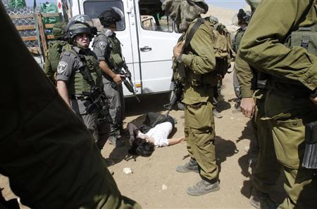 French diplomat Marion Castaing lays on the ground after Israeli soldiers carried her out of her truck containing emergency aid, in the West Bank herding community of Khirbet al-Makhul, in the Jordan Valley September 20, 2013. REUTERS/Abed Omar Qusini